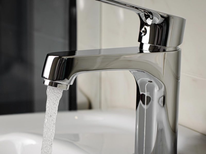 Water flows from the tap or faucet in bathroom. Copy space, close up